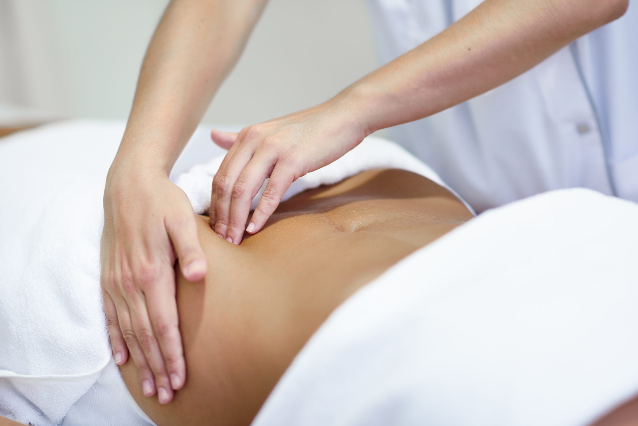Woman receiving a belly massage at spa salon Вісцеральний масаж — це м’який і глибокий вплив руками на область живота